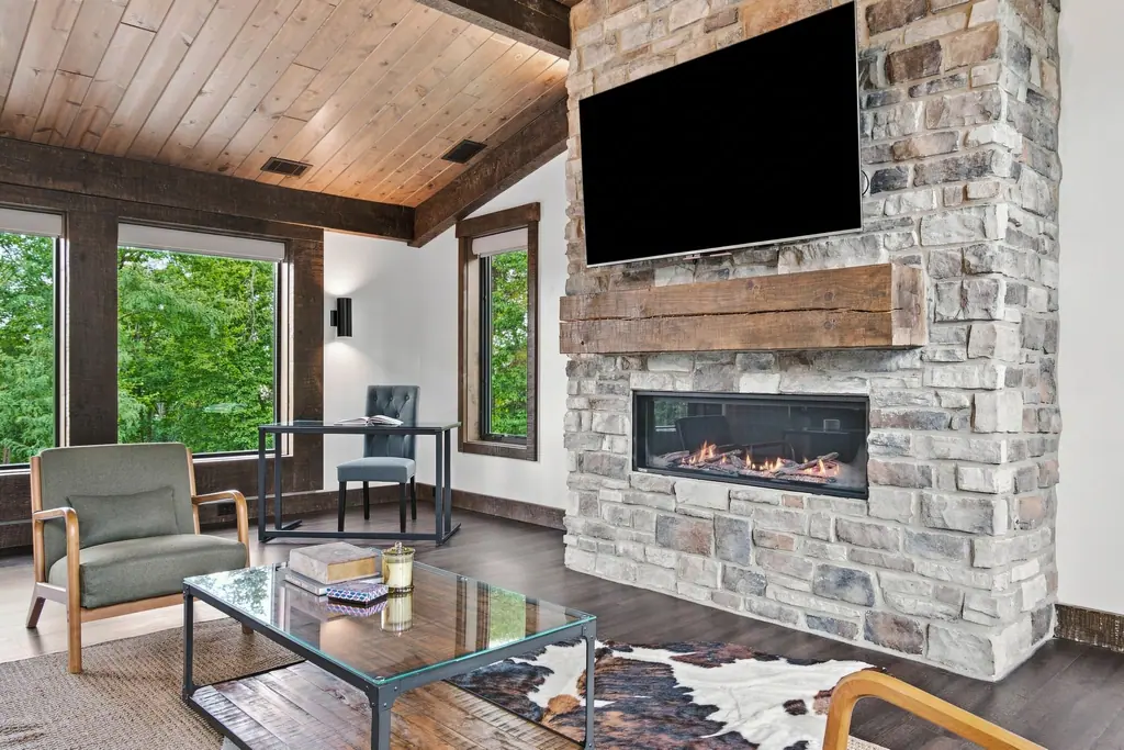 The third floor lounge: a gas fireplace in a stone wall under a wood ceiling, with a desk by the windows.